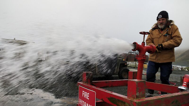 Plumber turning fire hydrant with water gushing