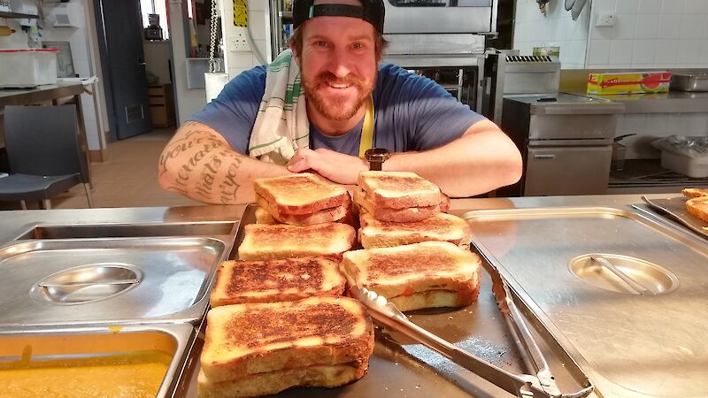 Expeditioner leaning on bain marie with toasted sandwiches