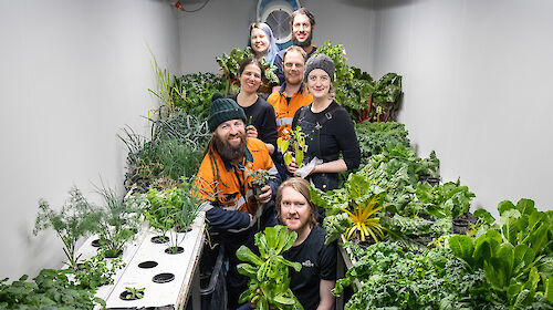 Group of expeditioners in the hydroponics shed with produce