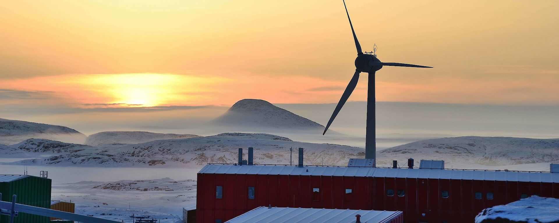 View of sunrise, mist buildings and large wind turbine