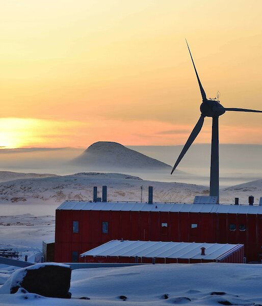 View of sunrise, mist buildings and large wind turbine