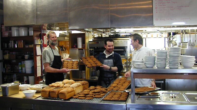 Expeditioners in aprons showing off a tray of biscuits