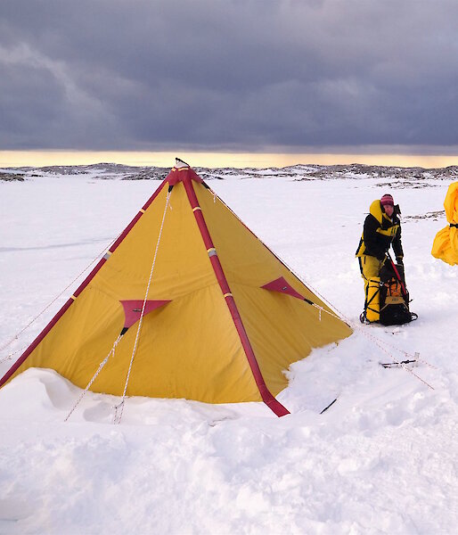 Expeditioners with backpacks standing near tent