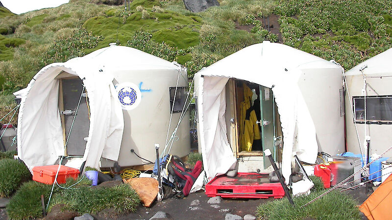 Three huts made out of poly water tanks with canvas porches