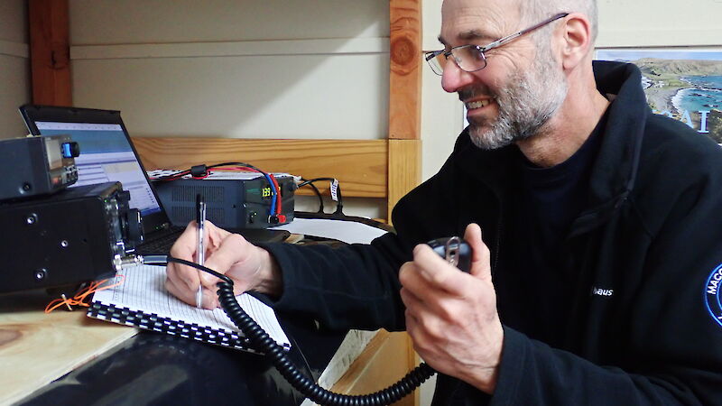 Man sitting at desk with notepad and ham radio