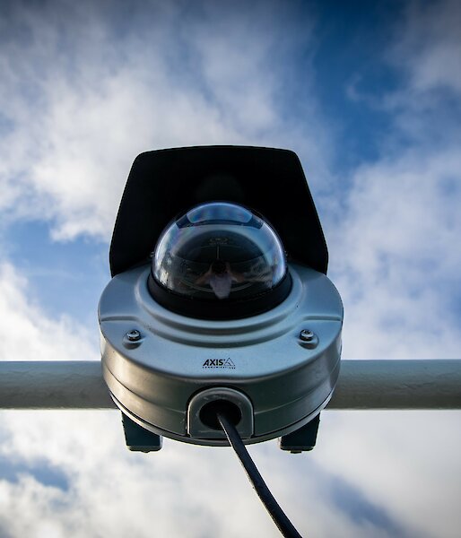 View of the webcam from below, showing the cylindrical camera body with hemispherical glass lens cover.