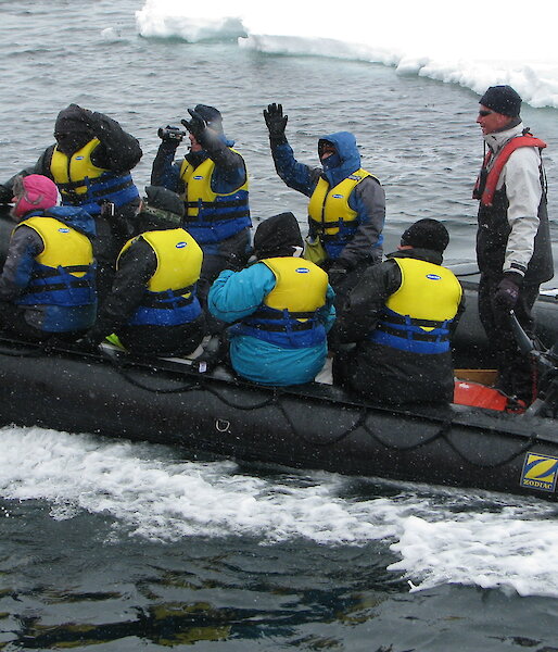 Eight tourists in an inflatable rubber boat, with an ice floe in the background