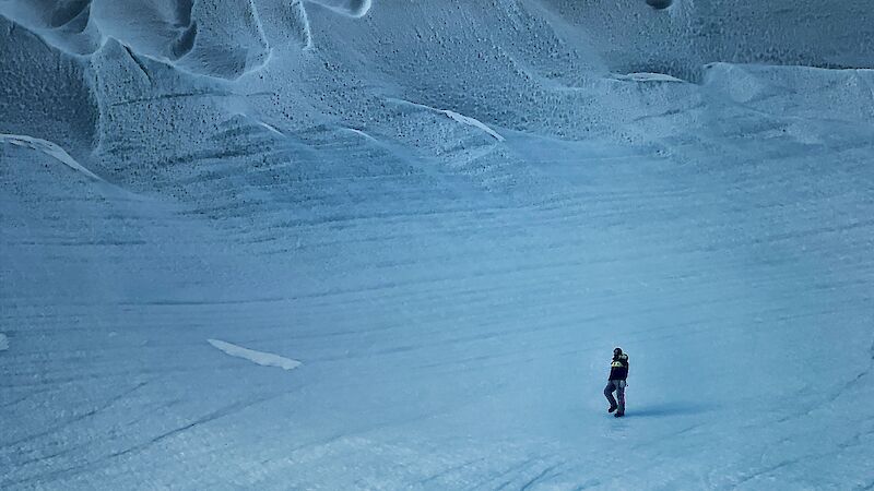 An expeditioner walking on the ice near mountains