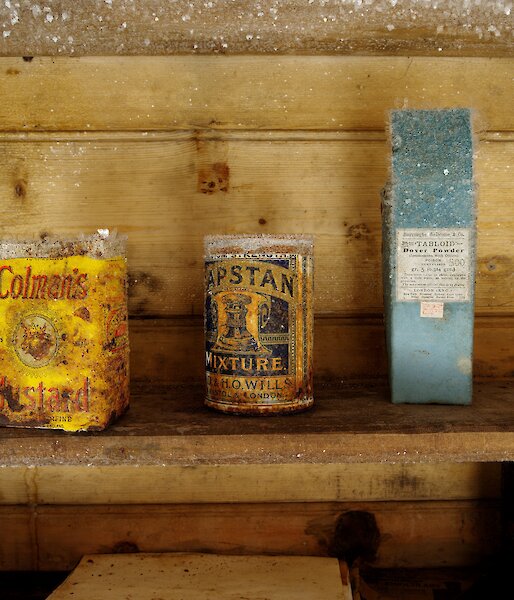 A row of tins on a shelf, covered in ice crystals.