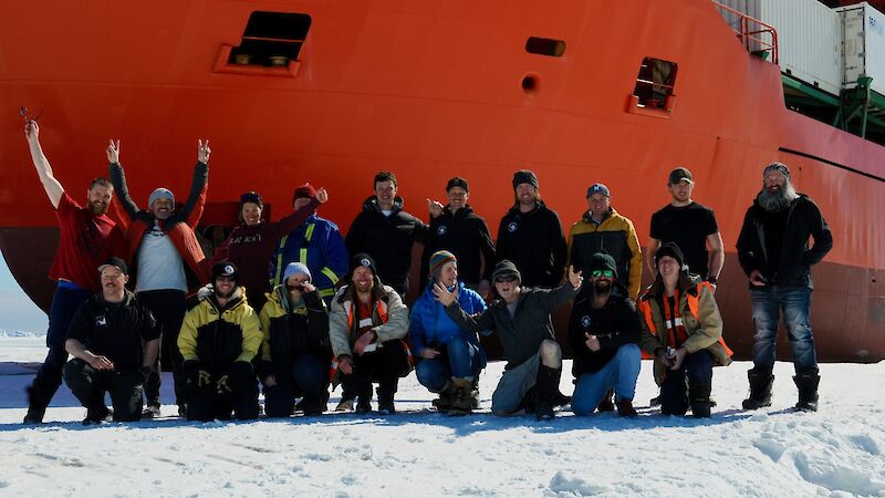 Group shot of expeditioners in front of ship parked in ice