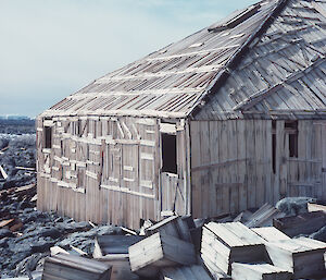 The hut still stands with old wooden boxes strewn on the ground behind.