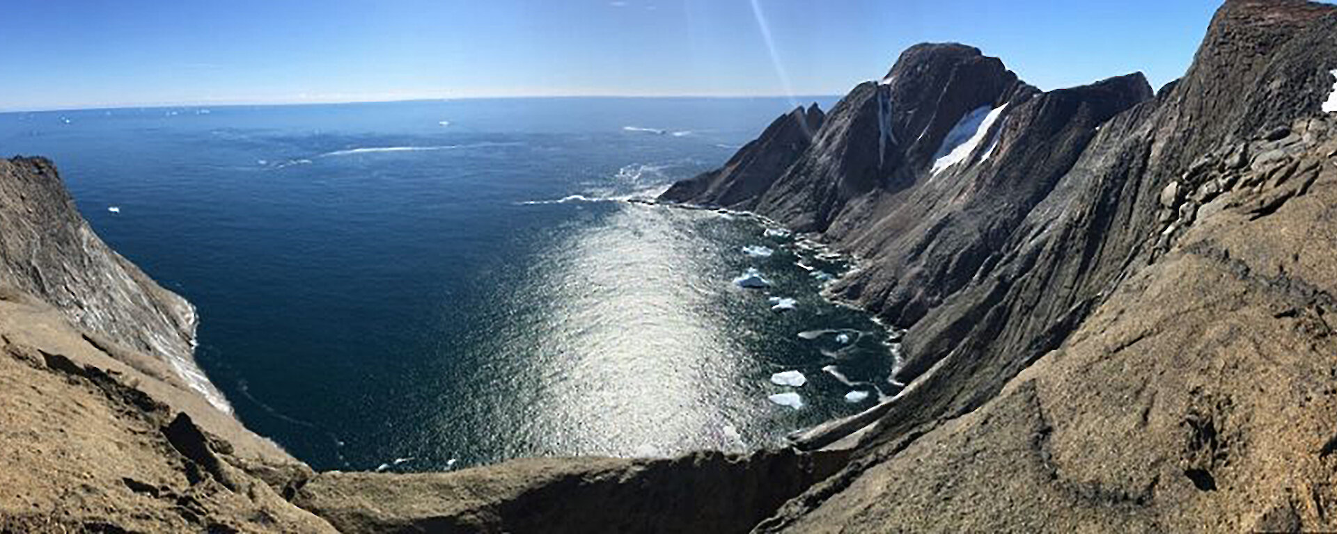 Panoramic view from high ice free out crop on coast over looking a sunlit ocean