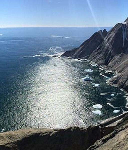 Panoramic view from high ice free out crop on coast over looking a sunlit ocean