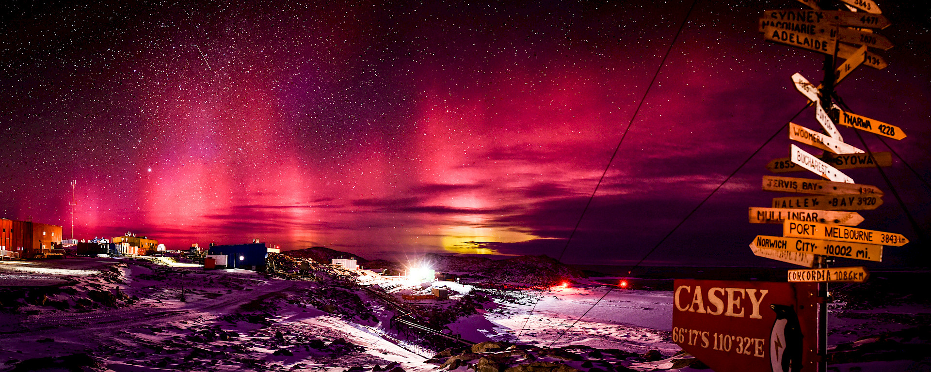 Panorama of the Aurora Australis in the red spectrum over Casey station on clear starry night