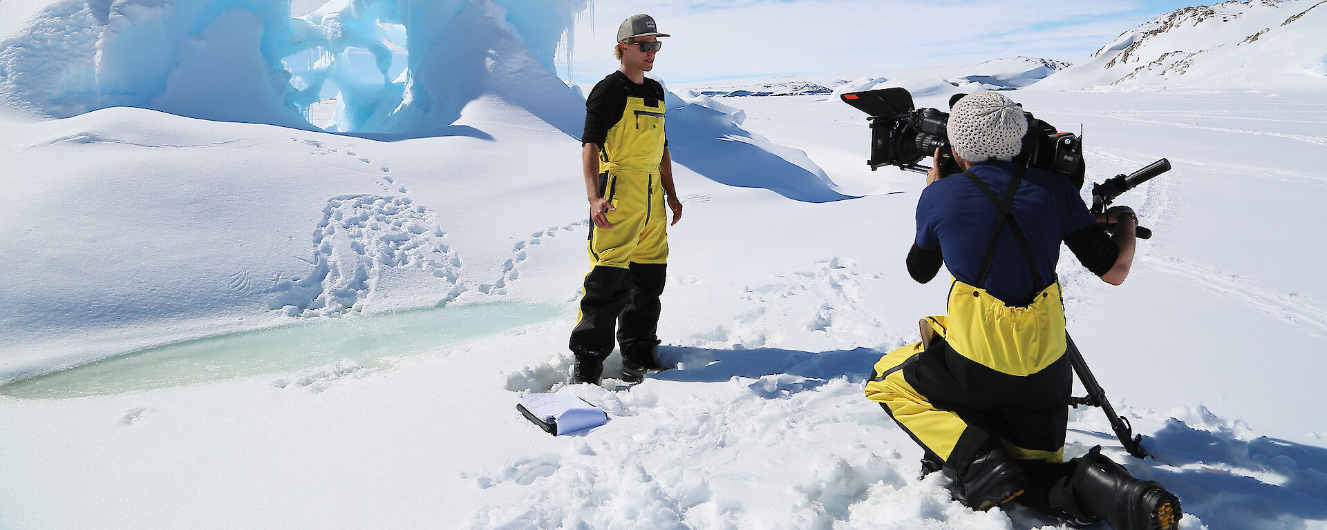 ABC3 presenter Kayne Tremills talks to the camera in front of wind eroded ice form