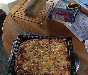 A pizza and loaf of bread made in a field hut.