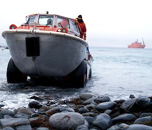 An amphibious vehicle drives up beach