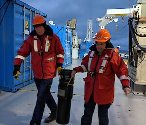 Two scientists carry a container of krill from the trawl net