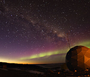Satellite dome at Davis research station under night sky with aurora