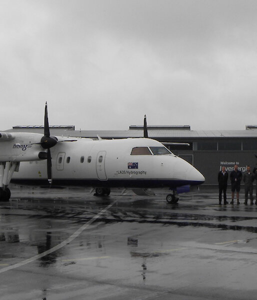 The Dash 8 on the runway at Invercargill with the nine person survey team standing beside.