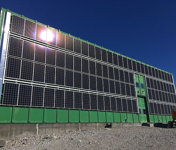 The 105 solar panel array installed, with a wind deflector visible down the length of the array on the left side of the building, to minimise the effects of high wind speeds during blizzards.