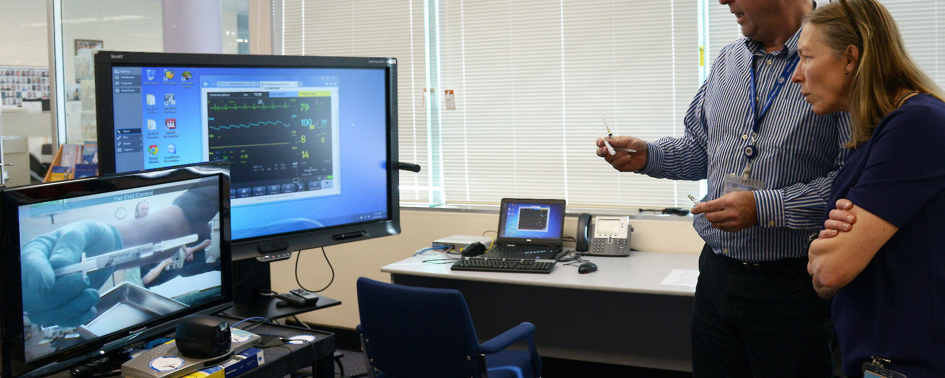 Chief Medical Officer, Dr Jeff Ayton, and another doctor viewing an Antarctic medical procedure remotely via a telemedicine monitor