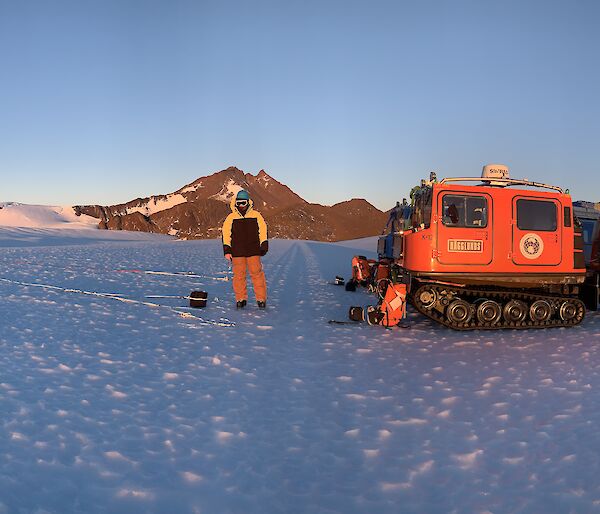 vehicles and expeditioners on ice with mountain in background