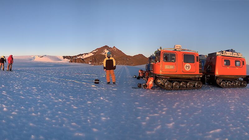 vehicles and expeditioners on ice with mountain in background