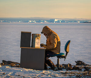 Expeditioner at ballot box with sea ice in background