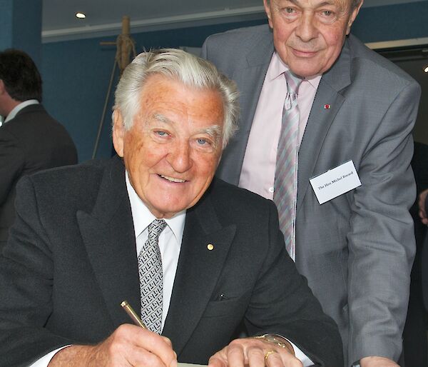 Former French Prime Minister Michel Rocard with former Australian Prime Minister Bob Hawke, signing a book.
