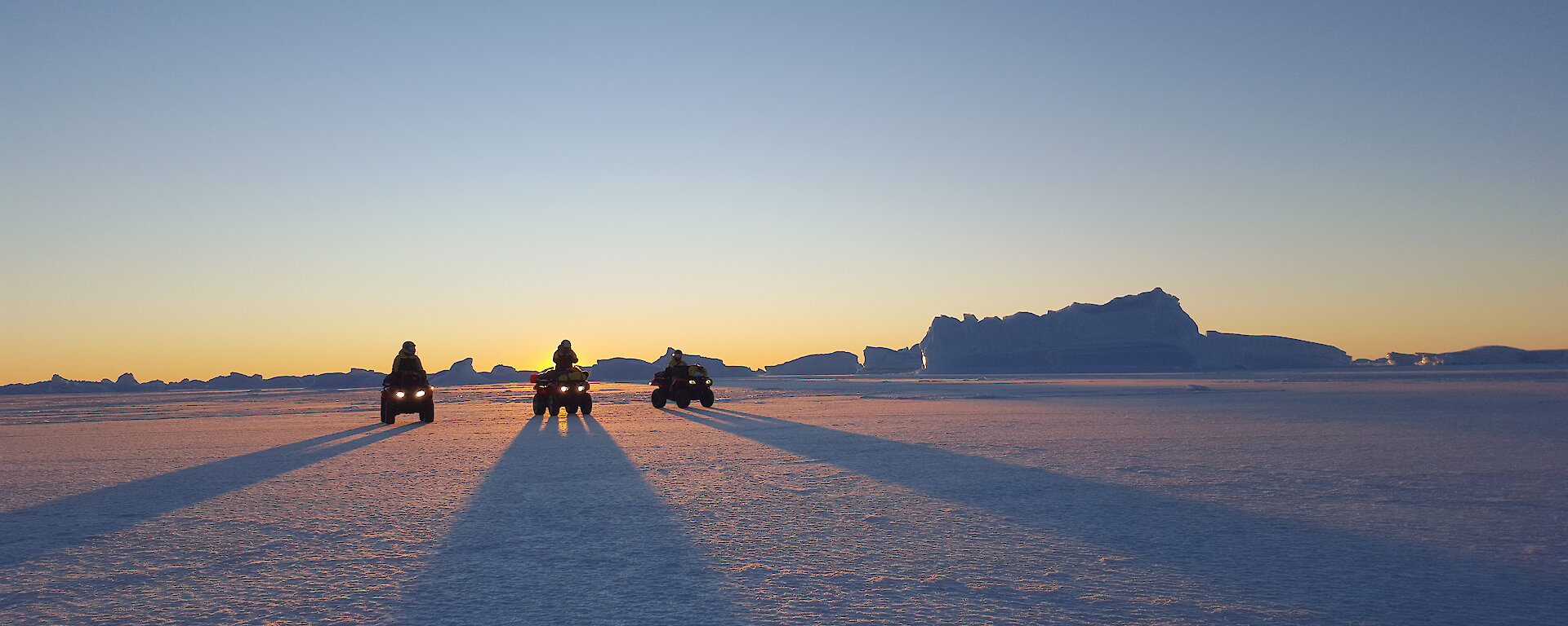 Quad bikes casting long shadows at sunset