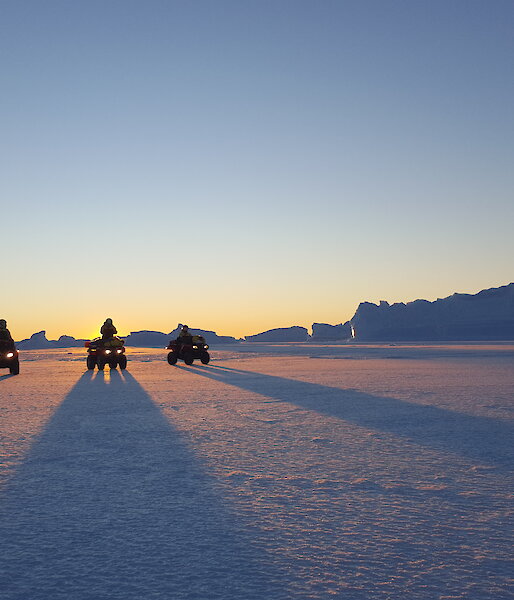 Quad bikes casting long shadows at sunset
