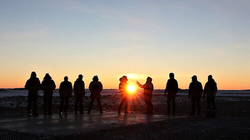 Expeditioners silhouetted against sunset