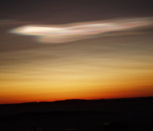 Bright white thin clouds above a dark sunset glow horizon