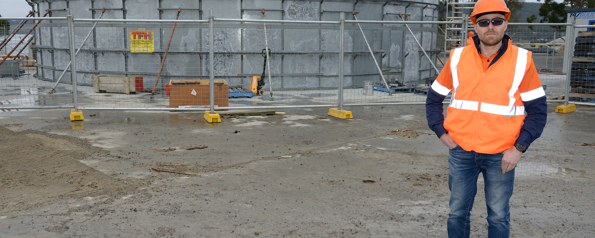 Man wearing high vis in front of partially constructed water tank