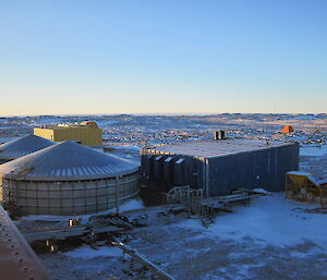 Two water tanks in the foreground with a yellow building in the background