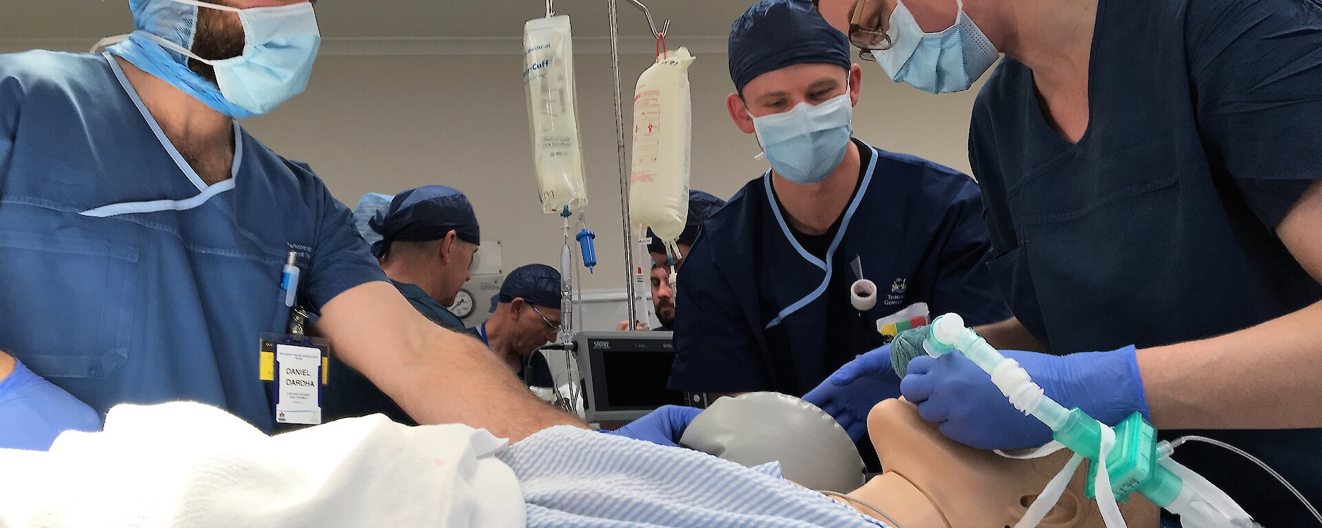 three people in an operating theatre with a mannequin