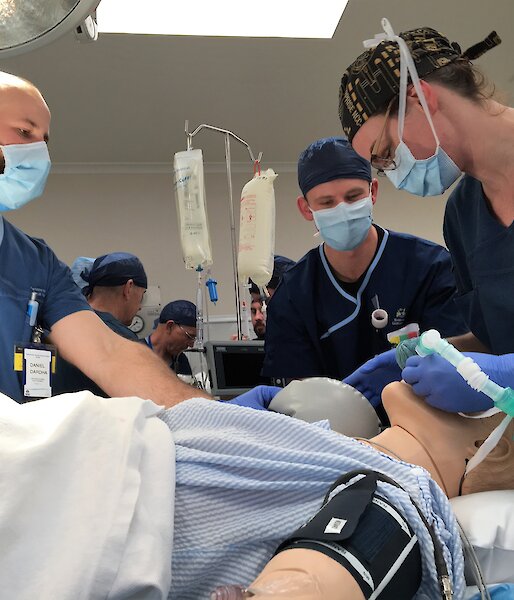 three people in an operating theatre with a mannequin