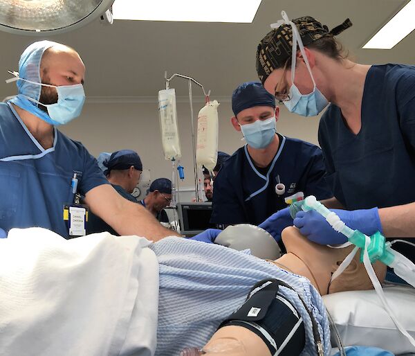 three people in an operating theatre with a mannequin