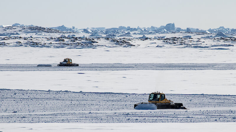 Two groomers preparing the sea-ice ski landing area in front Davis research station