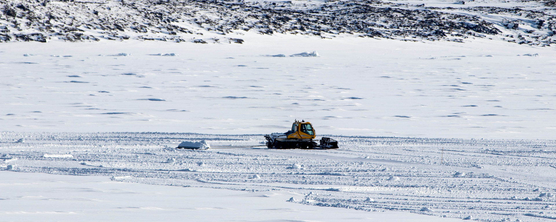 A drag beam is towed behind a snow groomer to flatten and distribute the snow over the landing area