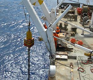 A sediment corer being deployed off the side of a ship.