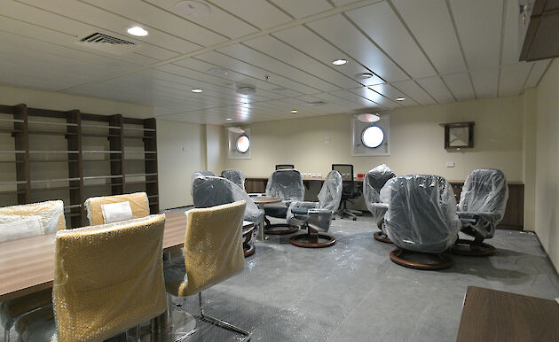 The library on the ship with empty bookshelves and seating.