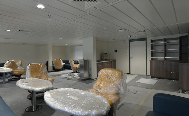 A lounge area on the ship with leather seats and small tables.