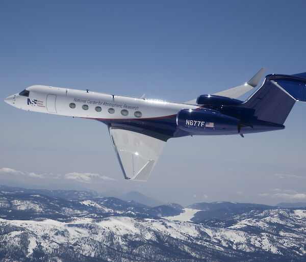 A Gulfstream V aircraft flying over mountains.