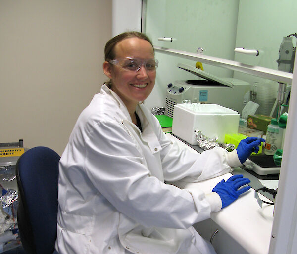 Leonie Suter in a lab coating sitting at a bench with test tube samples.