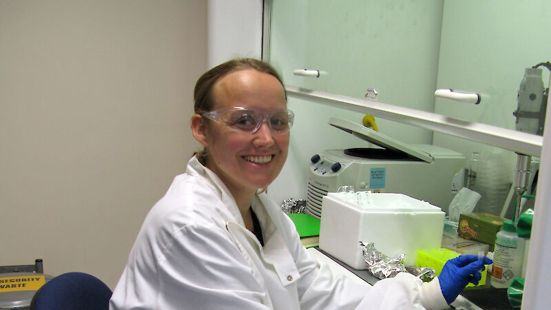 Leonie Suter in a lab coating sitting at a bench with test tube samples.