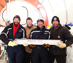 A team of international Aurora Basin scientists holding an ice core drilled at Aurora Basin North field camp