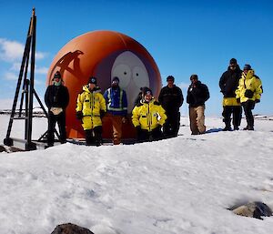 8 expeditioners standing in front of “Kenny” the shelter on the Mitchell Peninsula
