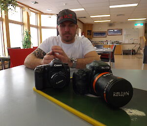 Justin sitting behind a cake made in the shape of a camera